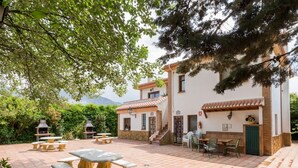 A courtyard with outdoor seating, a barbecue grill, and a building with a tiled roof. - Accommodation with pool and paddle tennis court (Padul)