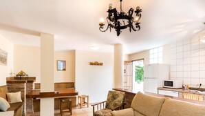 A spacious living area with a fireplace, a dining table, and a kitchen area with a microwave. - Accommodation with pool and paddle tennis court (Padul)