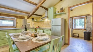 A kitchen with a dining table set for four, a refrigerator, and a window with a view of greenery. - Beautiful  villa for 7 guests with hot tub, private pool, WIFI, A/C, TV and pets allowed (Hum)