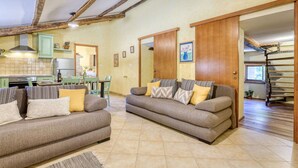 A cozy living room with two sofas, a dining table, and a kitchen in the background. - Beautiful  villa for 7 guests with hot tub, private pool, WIFI, A/C, TV and pets allowed (Hum)
