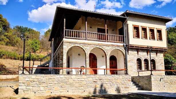 A two-story building with a stone facade, wooden balconies, and arched doorways. - Zenios Dionysos - Traditional villa overlooking Pindos (Grevena)