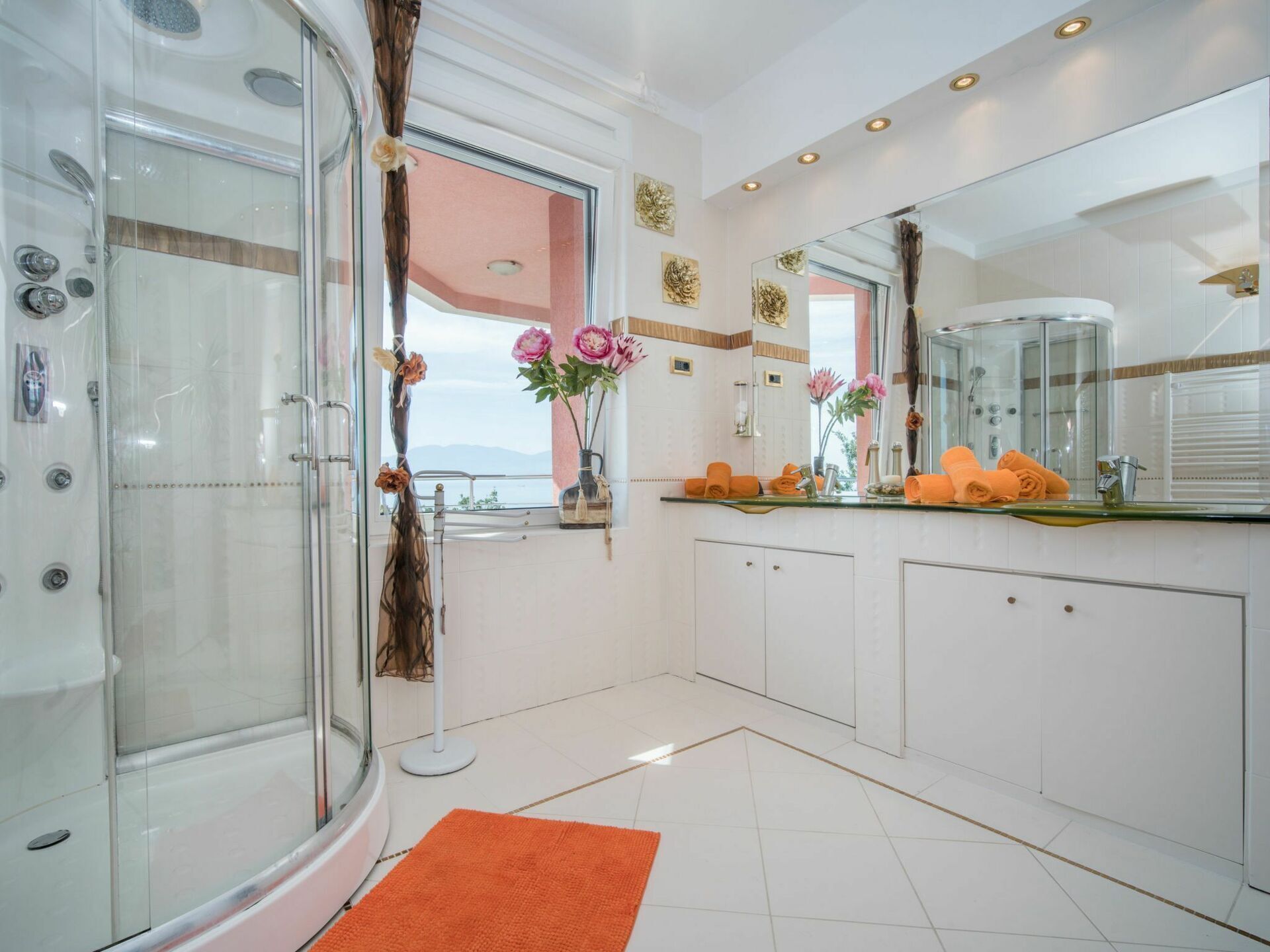 Une salle de bain moderne avec une douche en verre, un grand miroir et une vue sur la mer.