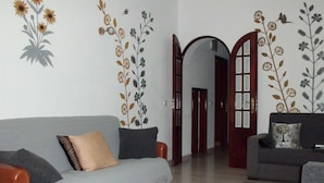 A living room with a grey sofa, a wooden door, and floral wall decals. - Private villa with a plunge pool near the beach, featuring 2 large terraces and a hi-fi system (Lagos)