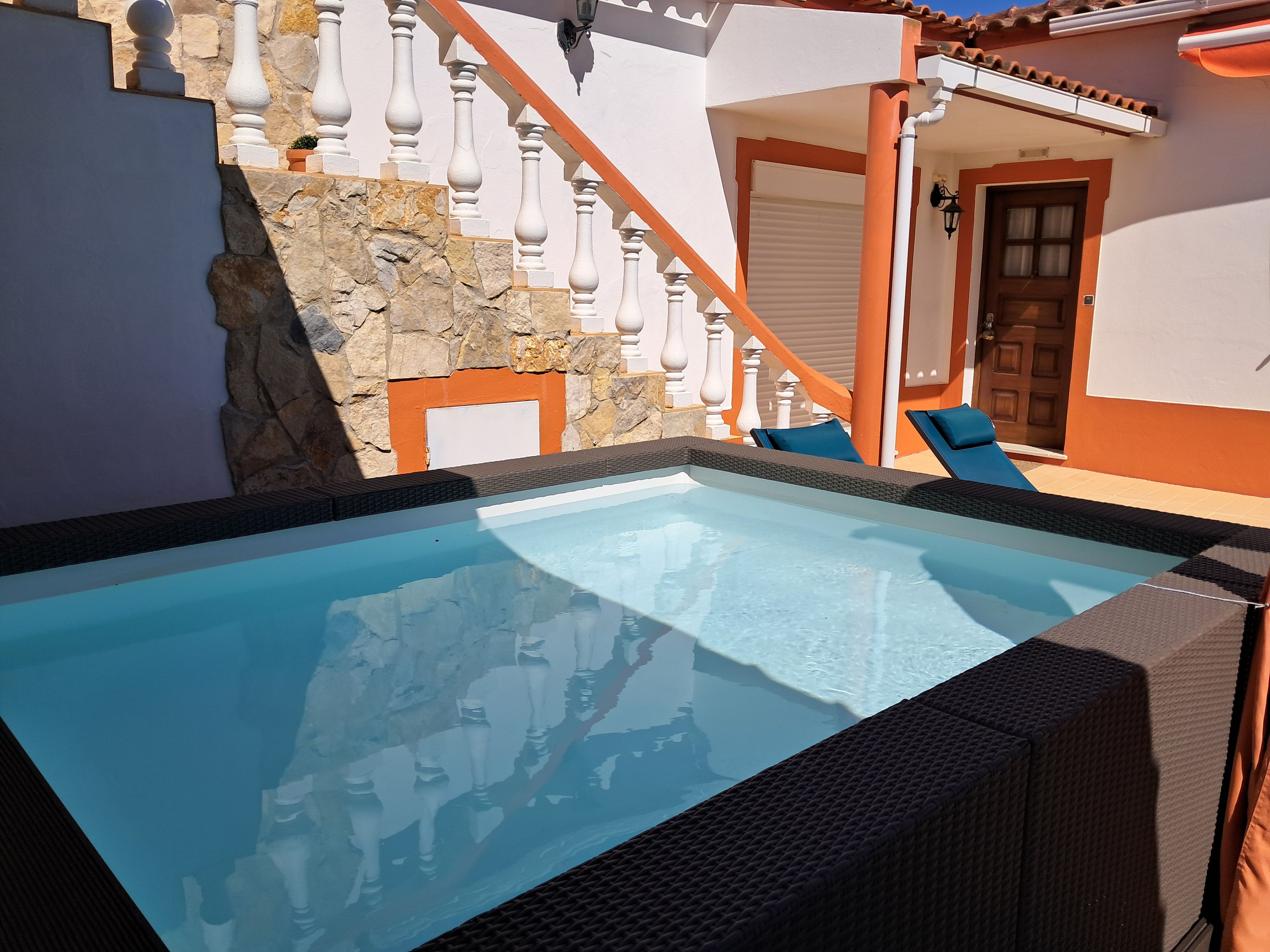 Une piscine avec un mur en pierre et un escalier en bois.