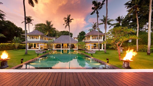 Un resort lujoso con una piscina grande, dos casas de huéspedes y una zona de terraza.
