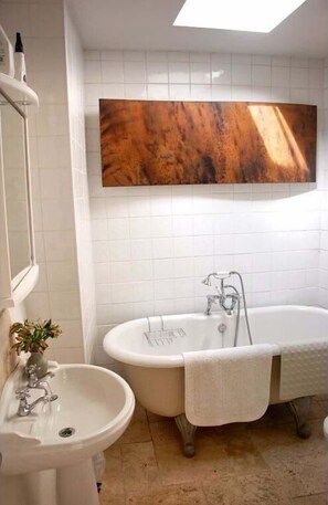 Bathroom features a bathtub, pedestal sink, and large mirror.