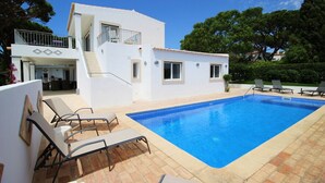 Ein zweistöckiges weißes Gebäude mit Swimmingpool, Außenbereich und Balkon.