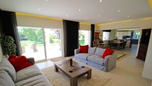 Ein modernes Wohnzimmer mit einer Couch, einem Couchtisch und einem Essbereich im Hintergrund.