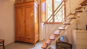 A staircase with wooden steps and metal railings, a wooden wardrobe, and a window with open shutters.