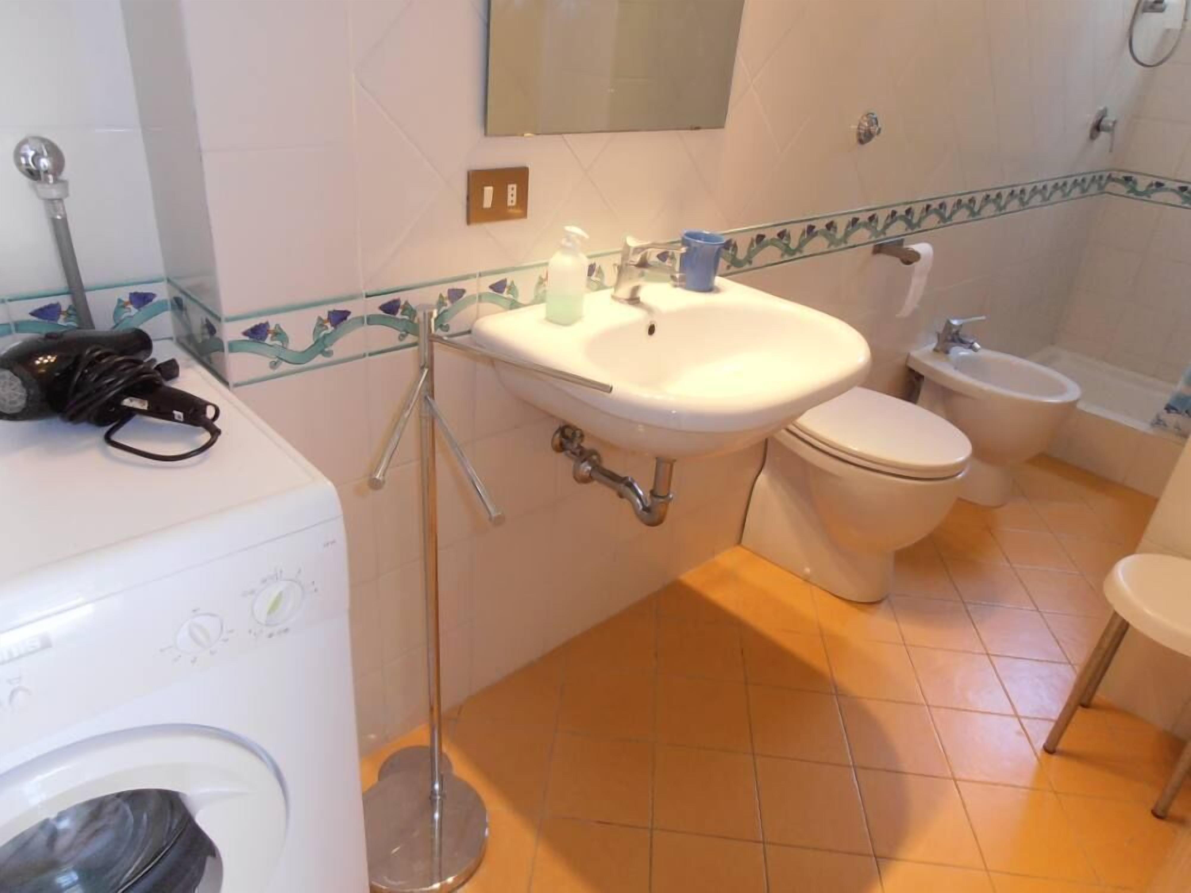 Une salle de bain équipée d’un lave-linge, d’un évier, de toilettes et d’un bidet.