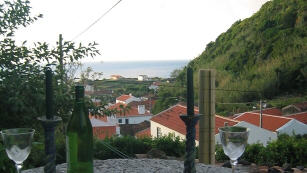 Mesa posta ao ar livre com vista para uma vila costeira e colinas.