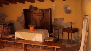 A rustic room with a wooden bench, a table with a white tablecloth, a potted plant, and a wooden door. - Casa Ollaga for 4 people (Olite)