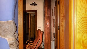 A wooden staircase leading to a room with a stone wall and a red chair. - Casa Ollaga for 4 people (Olite)