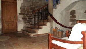 A rustic interior with a wooden door, stone wall, and a staircase with a metal railing. - Casa Ollaga for 4 people (Olite)