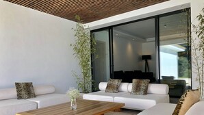 Una sala de estar moderna con un sofá blanco, una mesa de centro de madera y un ventanal que ofrece vistas al exterior.