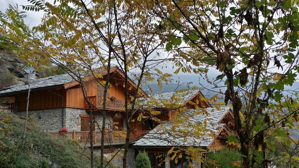 A rustic wooden house with stone walls, a stone staircase, and a garden with shrubs and a small tree. - Chalet with a beautiful view to comfortably enjoy nature in the Park and Valley (Introd)
