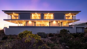 Een modern huis met twee verdiepingen, grote ramen en een plat dak.