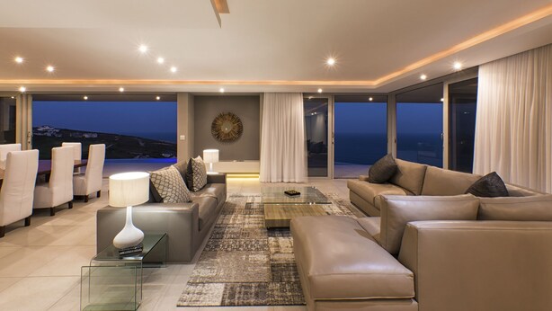 Een moderne woonkamer met een bank, fauteuils, een salontafel en uitzicht op de oceaan.