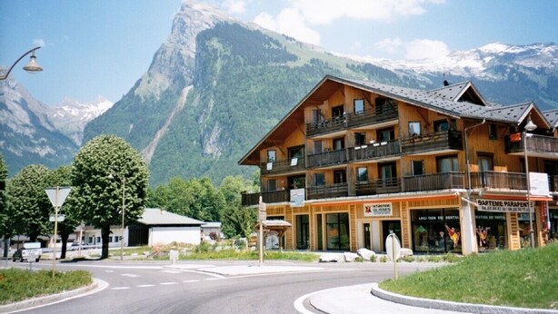 A wooden hotel with balconies, a sign for 'LOCI 30 RENTAL', and a mountain backdrop. - Rhodos 8 - 1 bedroom apartment 42m2 next to Grand Massif Express lift - NO WIFI (Samoëns)