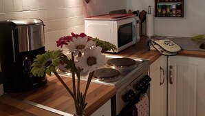 A kitchen with a stove, microwave, and coffee maker. There is a vase with flowers on the counter. - Rhodos 8 - 1 bedroom apartment 42m2 next to Grand Massif Express lift - NO WIFI (Samoëns)