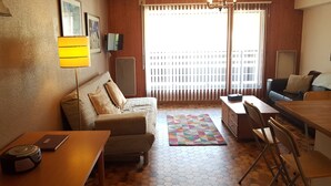 A cozy living room with a sofa, a dining table, a coffee table, and a chandelier. - Rhodos 8 - 1 bedroom apartment 42m2 next to Grand Massif Express lift - NO WIFI (Samoëns)