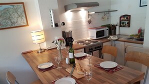 A dining area with a wooden table set for four, equipped with plates, cutlery, and wine glasses. A microwave, stove, and coffee maker are visible in the background. - Rhodos 8 - 1 bedroom apartment 42m2 next to Grand Massif Express lift - NO WIFI (Samoëns)