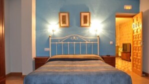 A bedroom with a bed, a wooden nightstand, a blue wall, and a door leading to another room. - Casa Rural Bocanegra for 2 people (Canicosa de la Sierra)