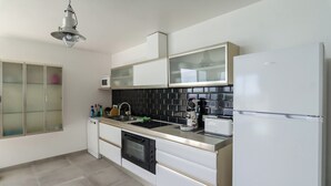A modern kitchen with white cabinets, a black tiled backsplash, a built-in oven, a microwave, a coffee maker, and a refrigerator. - Club Villamar - A beautiful modern Apartment with private pool and free Wi-Fi, with a view of the... (Lloret de Mar)