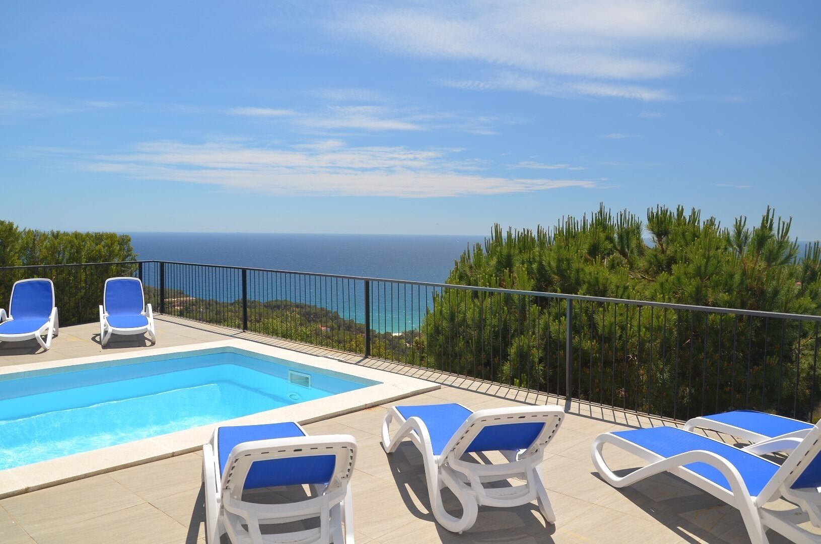 Un espace piscine avec des chaises longues et vue sur la mer.