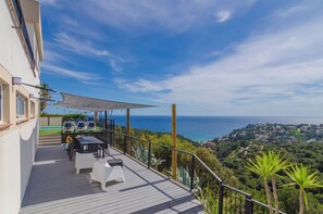 Enjoy the serene coastal view from this balcony with a table and chairs.