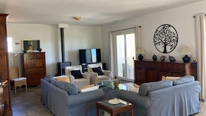 Een woonkamer met een zithoek, een televisie, een open haard en een decoratieve wanddecoratie van een boom.