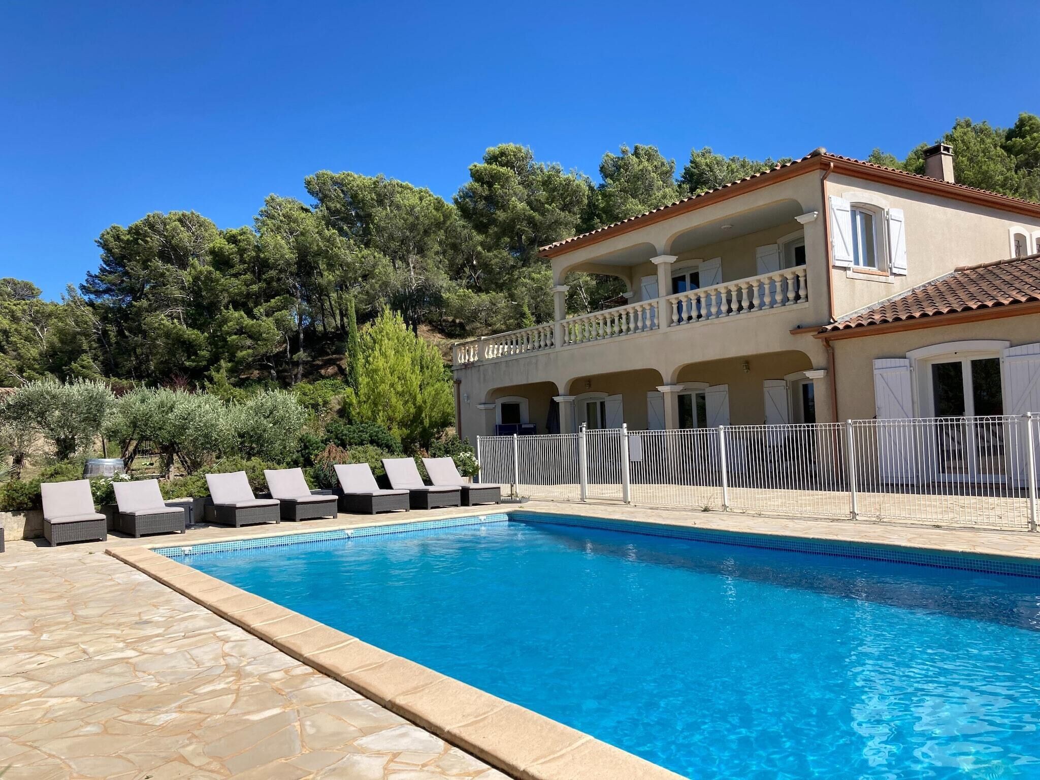 A pool area with lounge chairs, a pool, and a two-story building with balconies.