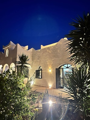 A building with a modern architectural style, featuring arched windows and a courtyard with plants. - Charming villa with private pool and cooker (ESSAOUIRA)