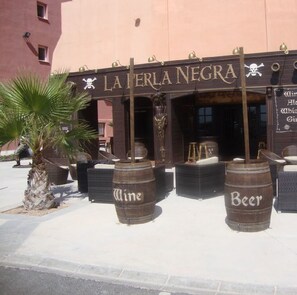 An outdoor seating area with wooden barrels labeled "Wine" and "Beer" in front of a building named "LATERA NEGRA".