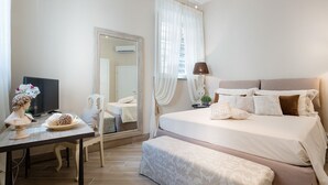 A bedroom with a bed, bedside table, lamp, and a mirror.