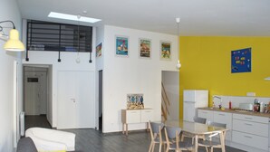 Ett modernt kök med en matplats, med bland annat ett vitt kylskåp, en gul vägg och en taklampa.