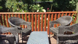 A deck with wicker furniture and a metal table. - Gower coast bungalow (Swansea City)