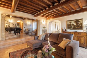 A spacious living area with a grand piano, a sofa, and a dining table. - Corte della Luna, elegant villa with swimming pool surrounded by a suggestive olive grove (Cortona)