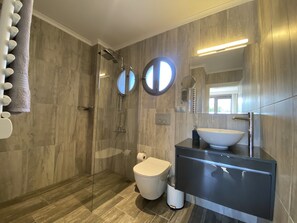 Une salle de bain moderne avec une douche à l’italienne, des toilettes et un meuble-lavabo doté d’un grand évier.