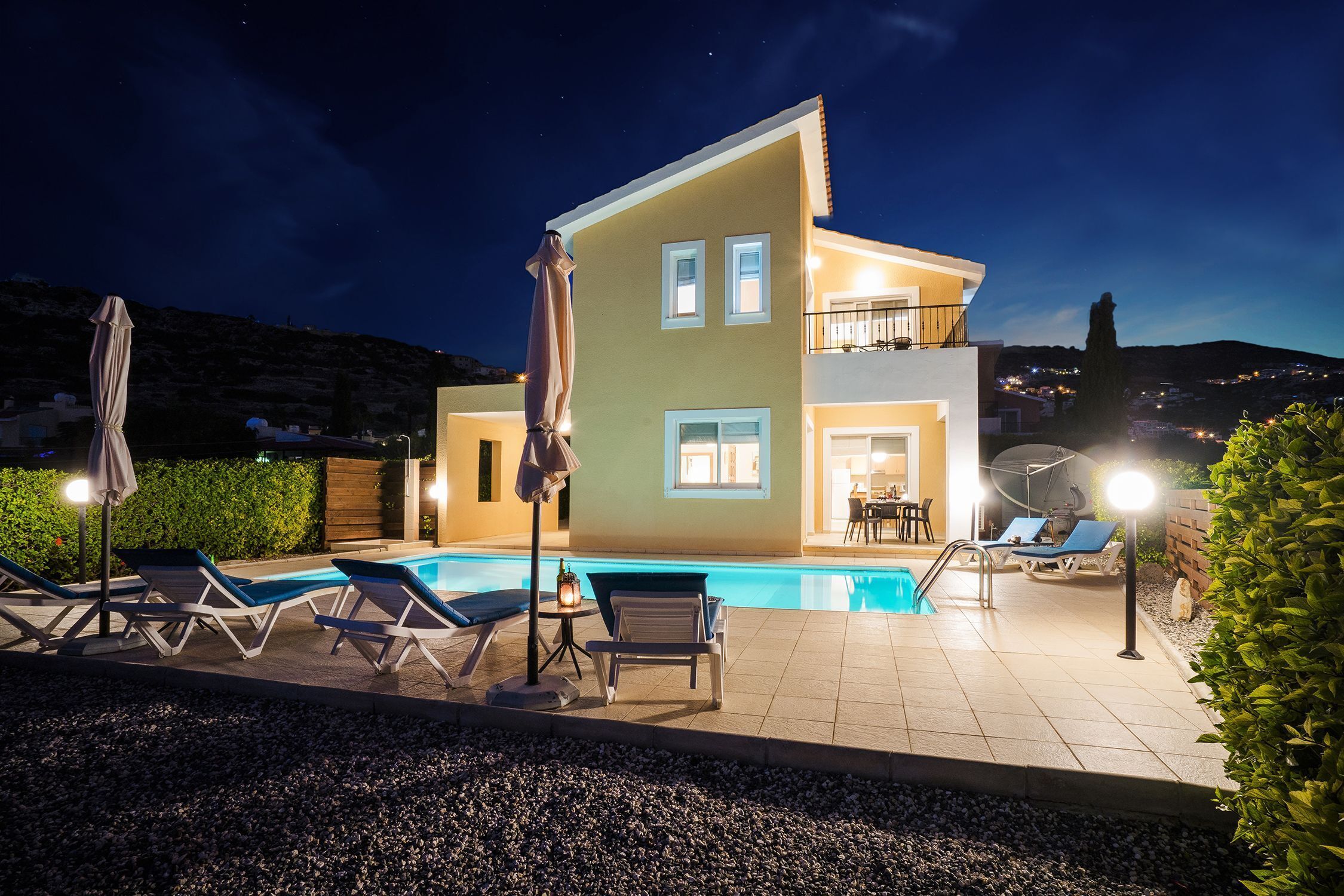 A two-story house with a swimming pool, outdoor seating, and a balcony.