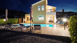 Une maison à deux étages avec une piscine, un espace salon extérieur et un balcon.