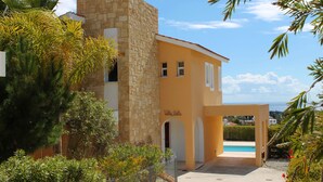 Un bâtiment à deux étages, doté d’une façade en pierre et d’une couleur jaune. On aperçoit une piscine à l’arrière-plan.