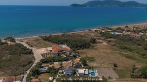 An aerial view of a coastal property with multiple buildings, a swimming pool, and a beach area.
