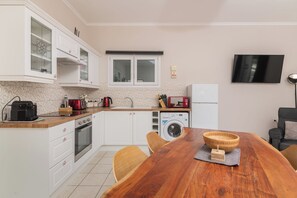 Enjoy meals in the kitchen with oven, microwave, and washing machine, and dine at the wooden table with a flat-screen TV above.