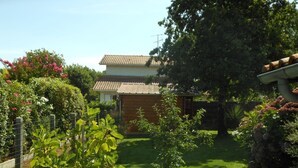 Una casa japonesa tradicional con techo de tejas, rodeada de un jardín cuidado con diversas plantas y una pequeña estructura de madera.