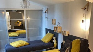 Un dormitorio con dos camas, cabeceros de madera, una mesita de noche, una cesta de mimbre y un espejo que refleja la habitación.