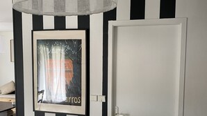 Una habitación con pared a rayas blancas y negras, un cuadro enmarcado y una puerta blanca.