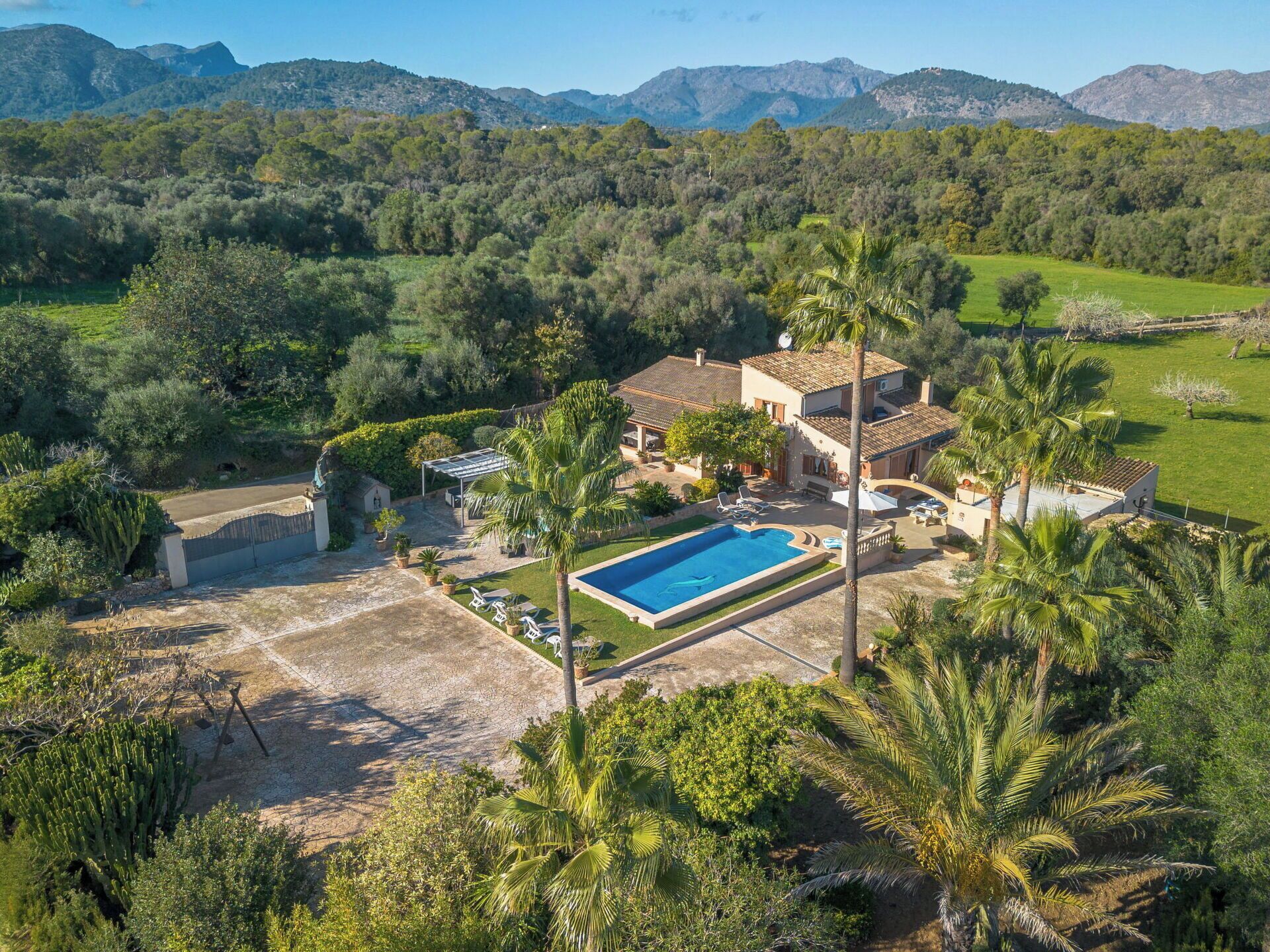 A villa with a swimming pool, surrounded by lush greenery and mountains.