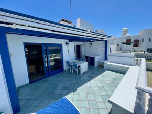 A rooftop terrace with a table and chairs, a pool, and a view of the surrounding buildings. - La Paloma Blanca-WELCOMEPLAYABLANCA (Playa Blanca)