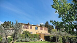 A two-story building with a yellow facade, multiple windows, and a garden in front. - Glicini 1, holiday home with pool 30' from Florence (Barberino Tavarnelle)